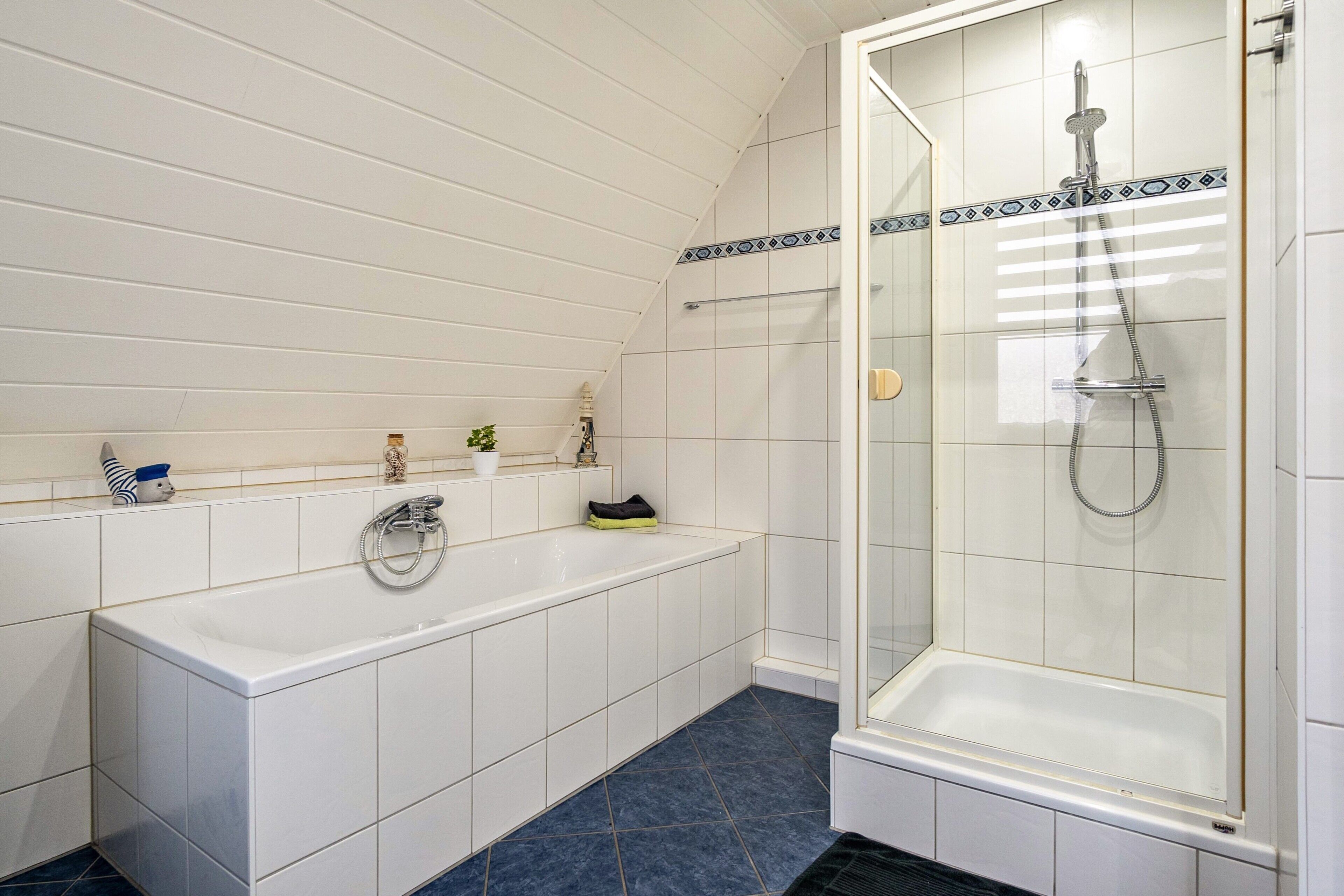 Een badkamer met een bad, douche en betegelde vloer.