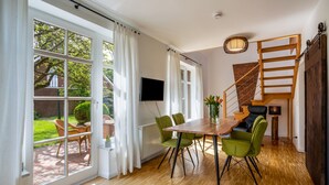 A dining area with a wooden table and green chairs, a staircase, and a view of the garden. - Holiday Home 'Altes Fischerhaus Döse' with Private Garden and Wi-Fi (Cuxhaven)