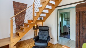 A staircase with wooden steps and a metal railing, a leather chair, and a wooden door. - Holiday Home 'Altes Fischerhaus Döse' with Private Garden and Wi-Fi (Cuxhaven)