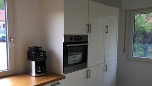 A kitchen with white cabinets, a built-in oven, and a coffee maker on the countertop.