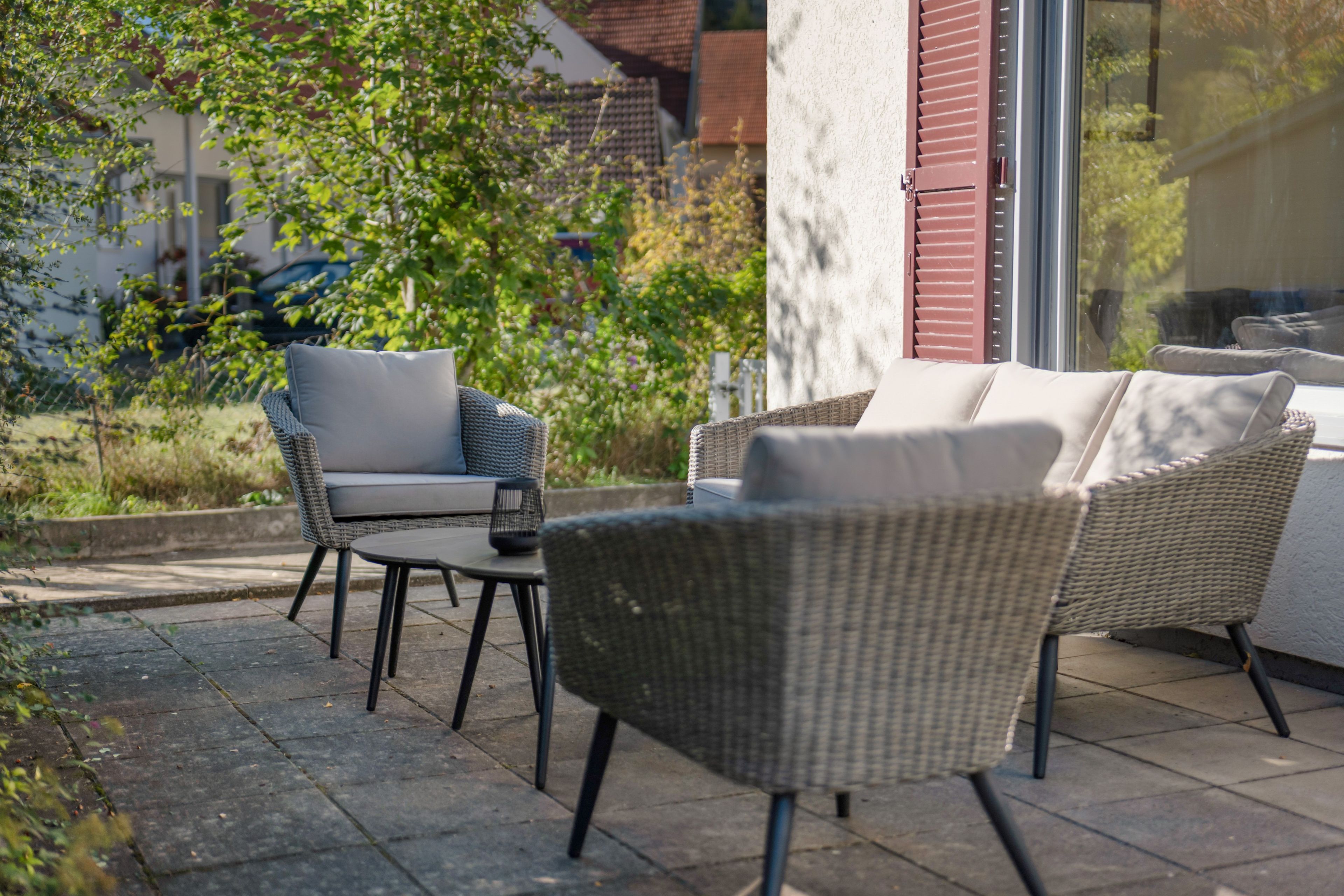 An outdoor seating area with wicker furniture and a glass door leading to a patio.