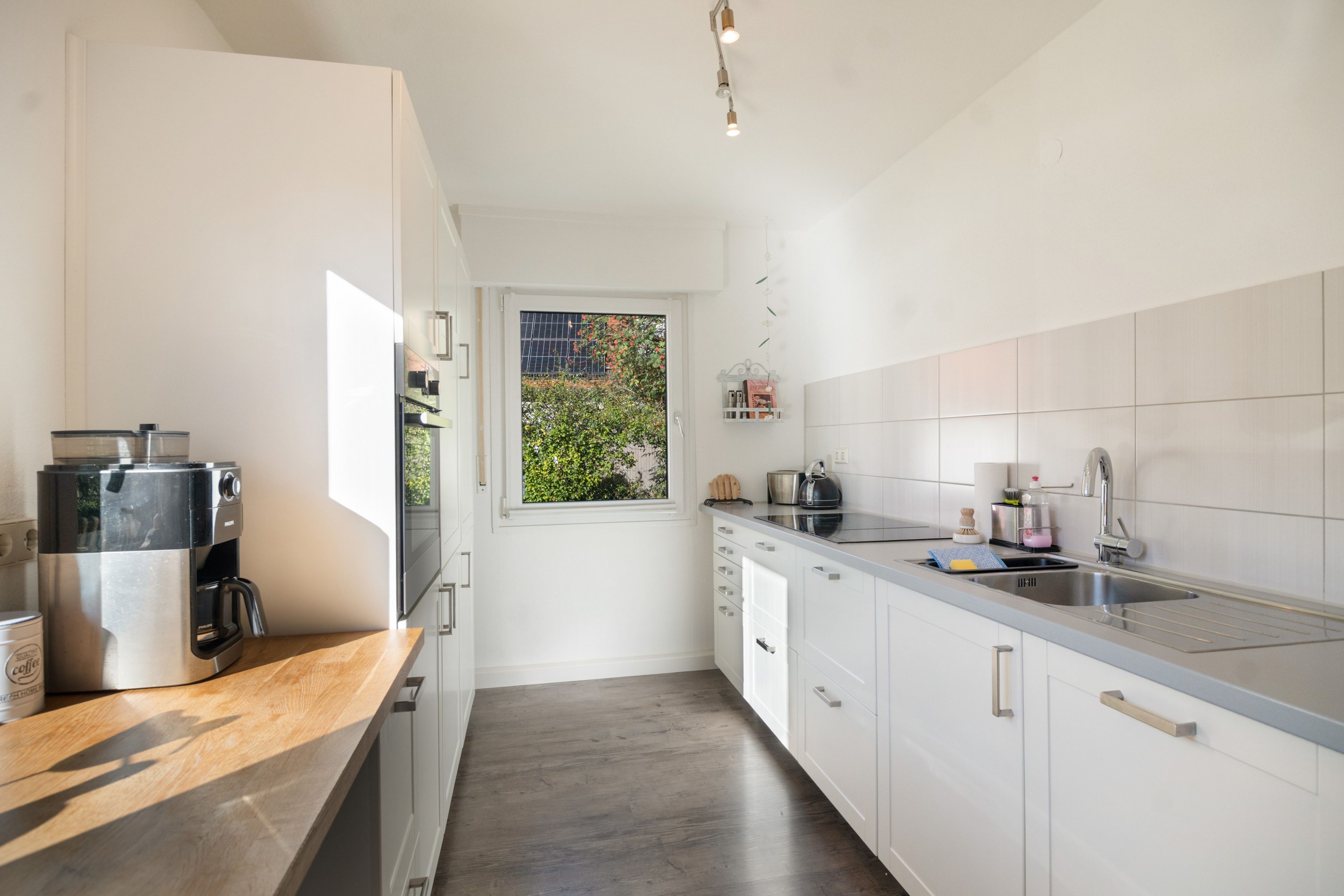 Eine moderne Küche mit Kaffeemaschine, Spüle und einem Fenster mit Blick auf Grünflächen.