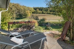 A patio with a table and chairs, a stone wall, and a view of a rural landscape.