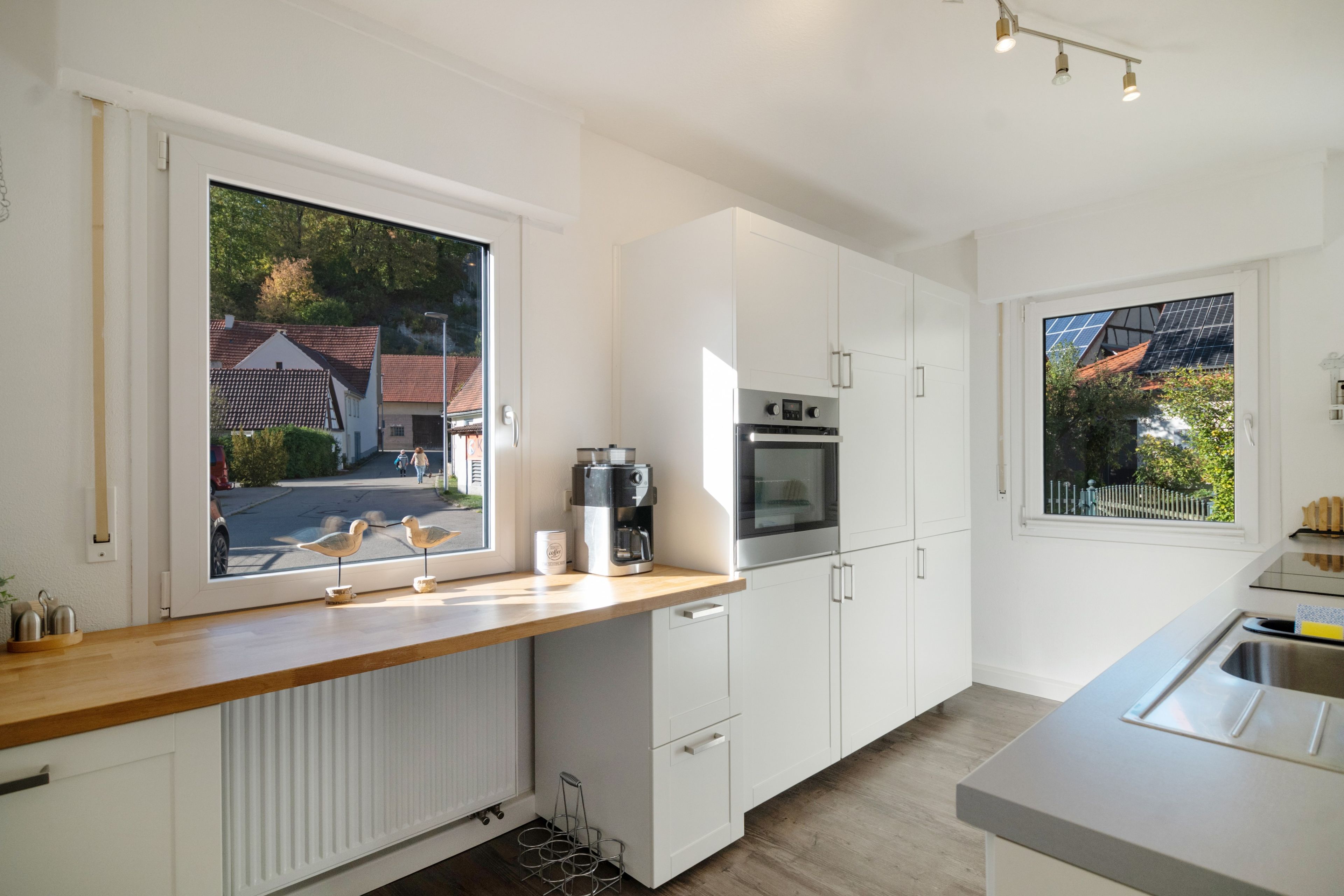 A modern kitchen with white cabinetry, a built-in oven, and a coffee maker on the counter.