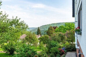 Zona residencial com uma casa, vegetação exuberante e uma paisagem acidentada ao fundo.