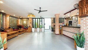Un hall d’entrée spacieux comprenant un comptoir d’accueil, un espace salon et une grande fenêtre laissant entrer la lumière naturelle.