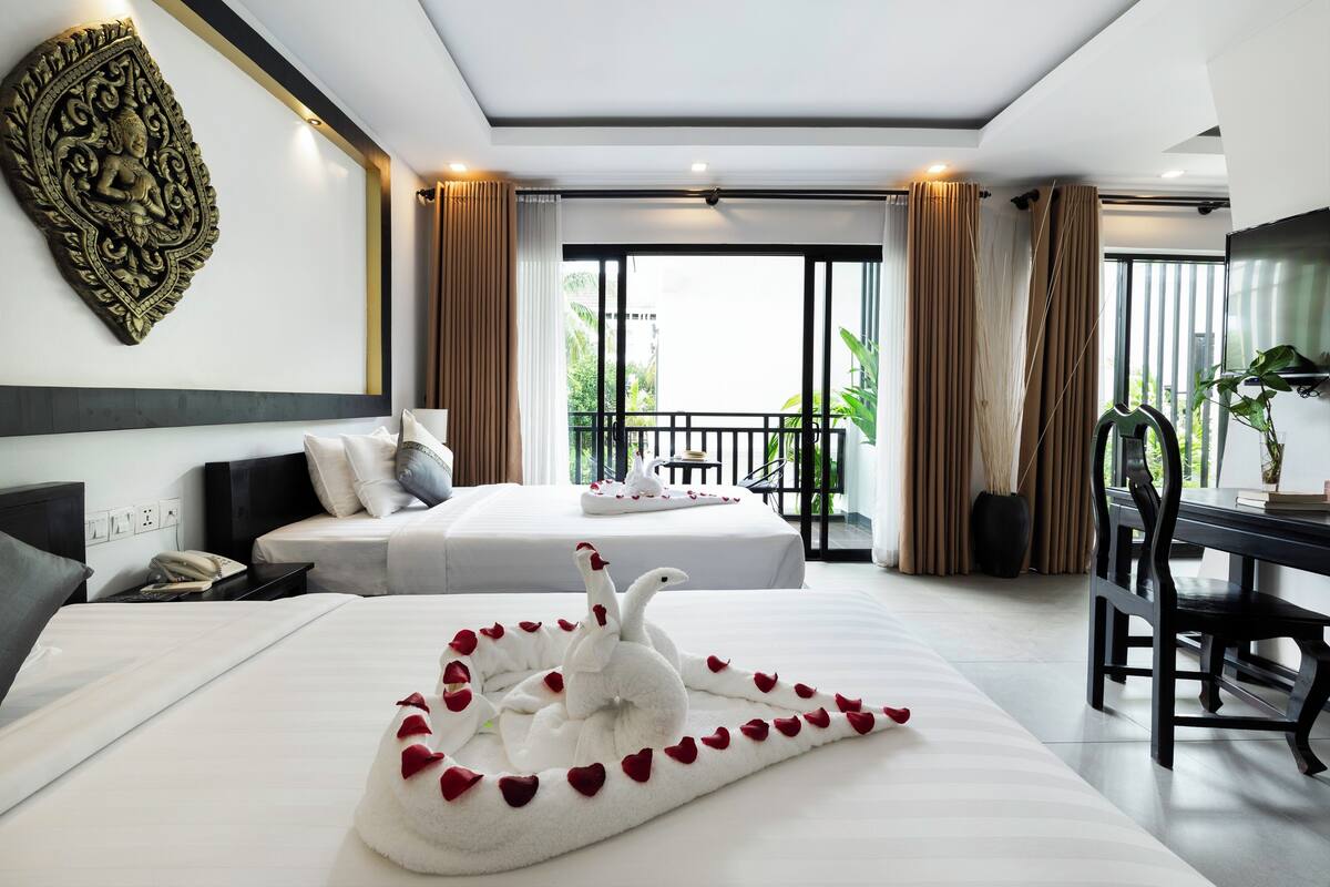 Une chambre d’hôtel avec deux lits, une table à manger et un centre de table décoratif en forme de cygne.