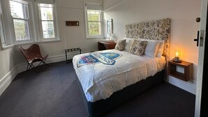 Une chambre à coucher avec un grand lit, deux tables de chevet, une chaise et une fenêtre.