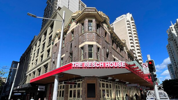 Le bâtiment Resch House se distingue par son auvent rouge bien visible et un panneau indiquant qu’il est interdit de tourner à gauche.
