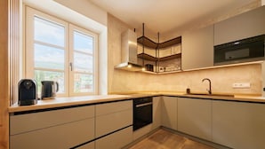 Een moderne keuken met een groot raam, inbouwapparatuur en een houten aanrecht.