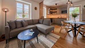 Een moderne woonkamer met een modulaire bank, een ronde salontafel en een eethoek met tafel en stoelen.