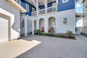 A two-story house with a covered porch, white columns, and a red door. - All-new waterfront home with on-site pool, golf, & easy beach access (Port Aransas)