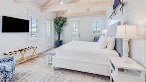 Quarto com cama grande, televisão na parede, planta em vaso e teto de madeira.