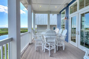 A covered outdoor area with Adirondack chairs and a view of the water. - All-new waterfront home with on-site pool, golf, & easy beach access (Port Aransas)