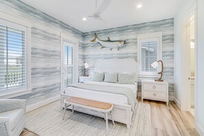 A bedroom with a bed, bedside tables, a bench, and a ceiling fan. - All-new waterfront home with on-site pool, golf, & easy beach access (Port Aransas)