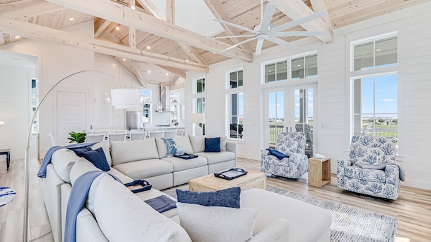 Uma sala de estar ampla com teto alto, grandes janelas e vista para o exterior.