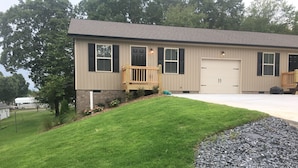 A two-story house with a front porch, a garage, and a well-maintained lawn. - Cozy Retreat • King Bed & Kitchen Near Lee (Cleveland)