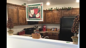 A kitchen with wooden cabinets, a black refrigerator, and two potted apple trees. - Cozy Retreat • King Bed & Kitchen Near Lee (Cleveland)