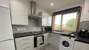Een compacte keuken met een gasfornuis, magnetron, oven en een ingebouwde wasmachine.