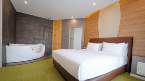 Una habitación de hotel moderna con una cama grande, una bañera separada y una alfombra verde.