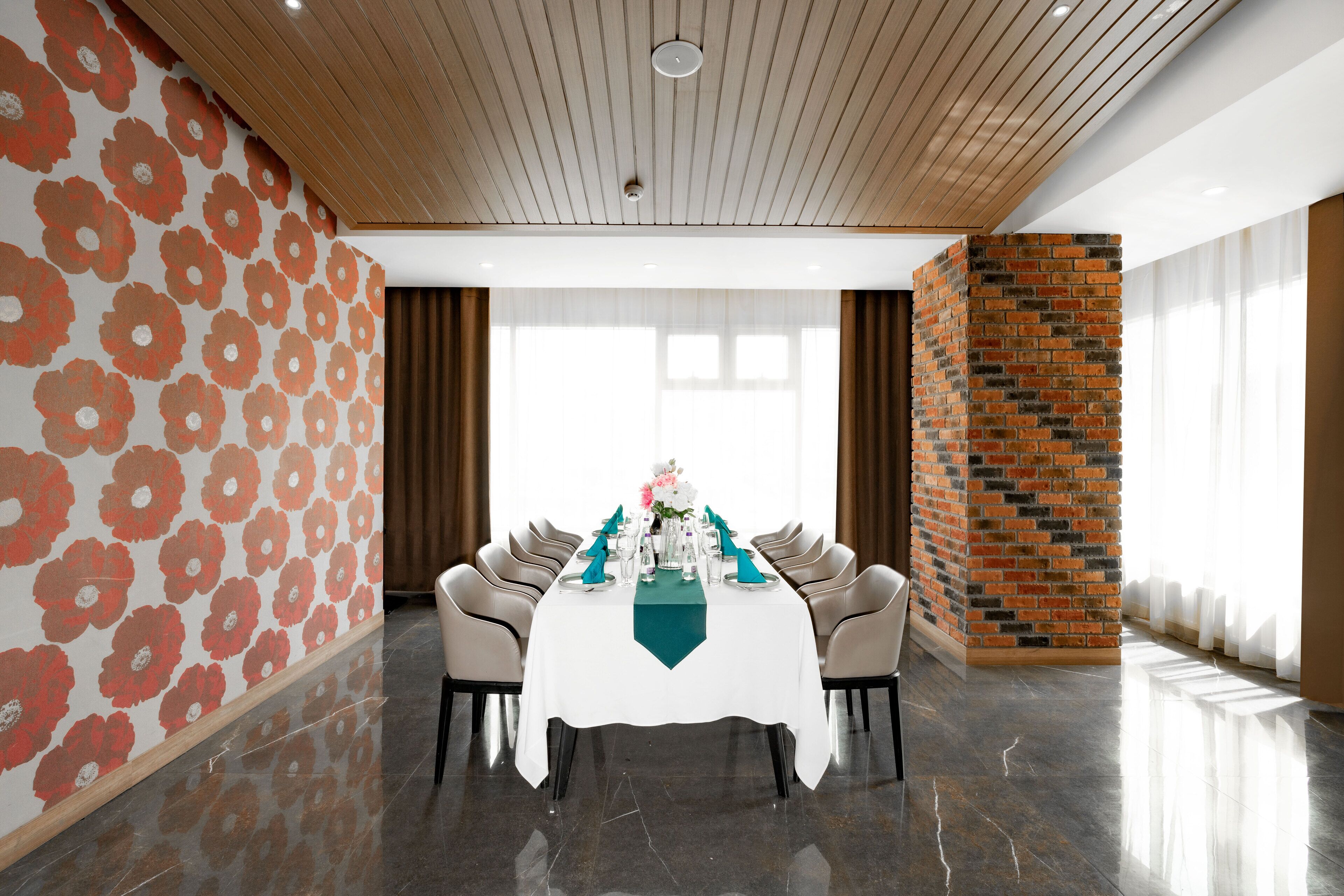 A conference room with a white table, chairs, and a brick accent wall.