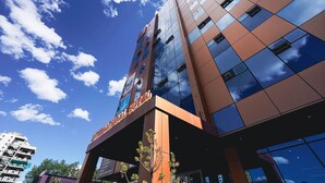 Un hotel moderno con fachada de vidrio que refleja el cielo y las nubes.