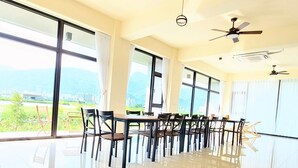 A spacious room with large windows, a dining area with chairs and tables, and ceiling fans. - Xian Jing B&B (Jiaoxi)