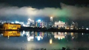 A nighttime cityscape with illuminated buildings reflected in a calm body of water. - Xian Jing B&B (Jiaoxi)