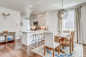 A modern kitchen with white cabinetry, a central island with stools, and a hanging light fixture.