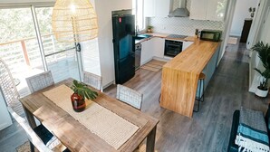 A modern kitchen with a wooden island, a refrigerator, and a microwave. - Tallowood Treehouse  (East Ballina)
