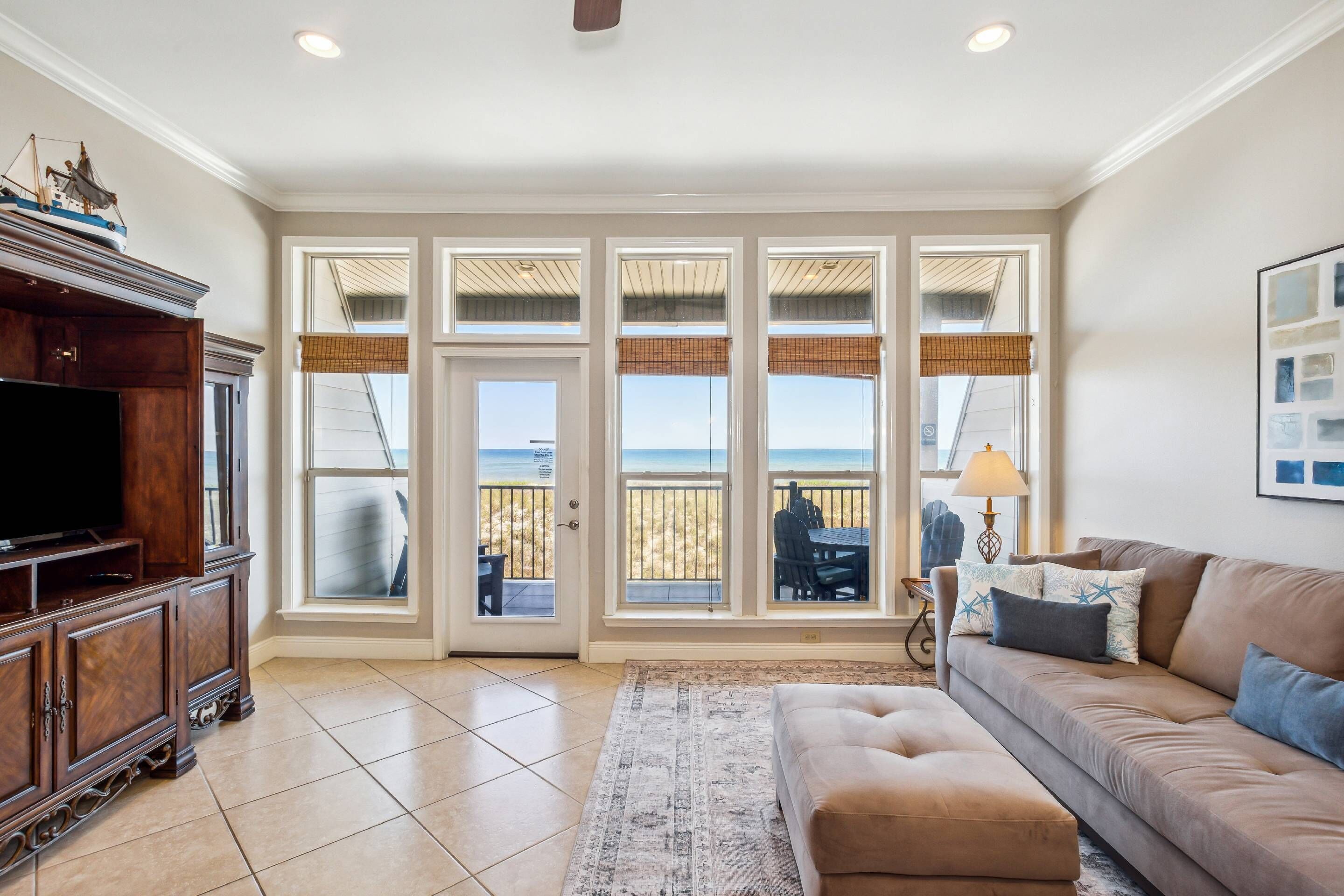 A living room with a large window, a television, a sofa, and a rug.