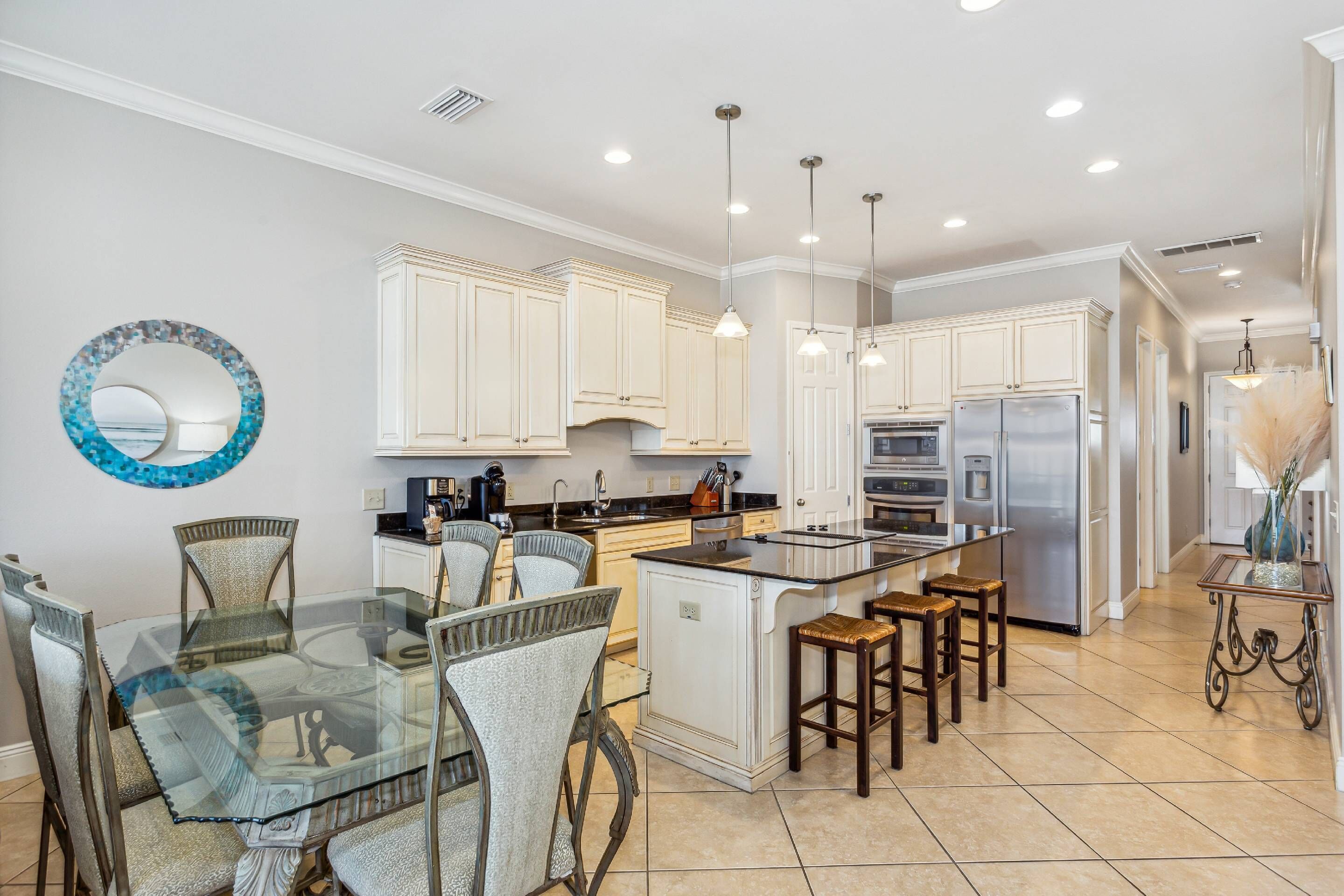 A modern kitchen with white cabinetry, a glass dining table, and a central island.