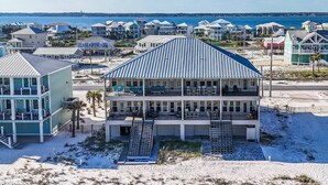 A beachfront property with a large, multi-story building featuring balconies and a covered patio area.