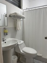 Un baño con lavamanos, inodoro y cortina de ducha blancos.