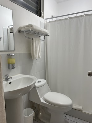 A bathroom with a white sink, toilet, and shower curtain. - Inari Guatemala (Guatemala City)