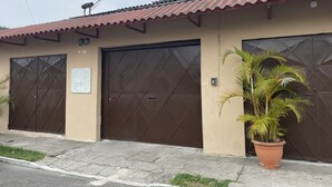 A building with two large, dark brown doors, a beige exterior, and a tiled roof. - Inari Guatemala (Guatemala City)