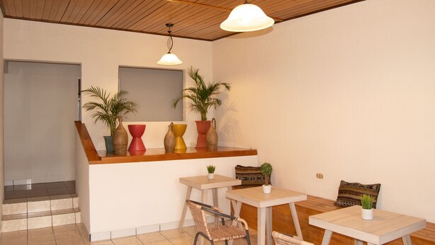 A modern interior with a wooden ceiling, a kitchen counter with decorative vases, and a seating area with two tables and chairs. - Inari Guatemala (Guatemala City)