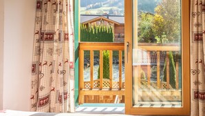 A room with a large sliding glass door leading to a balcony with a wooden railing and a view of a mountain landscape. - Riverside chalet with terrace and sauna in Kaprun (Kaprun)