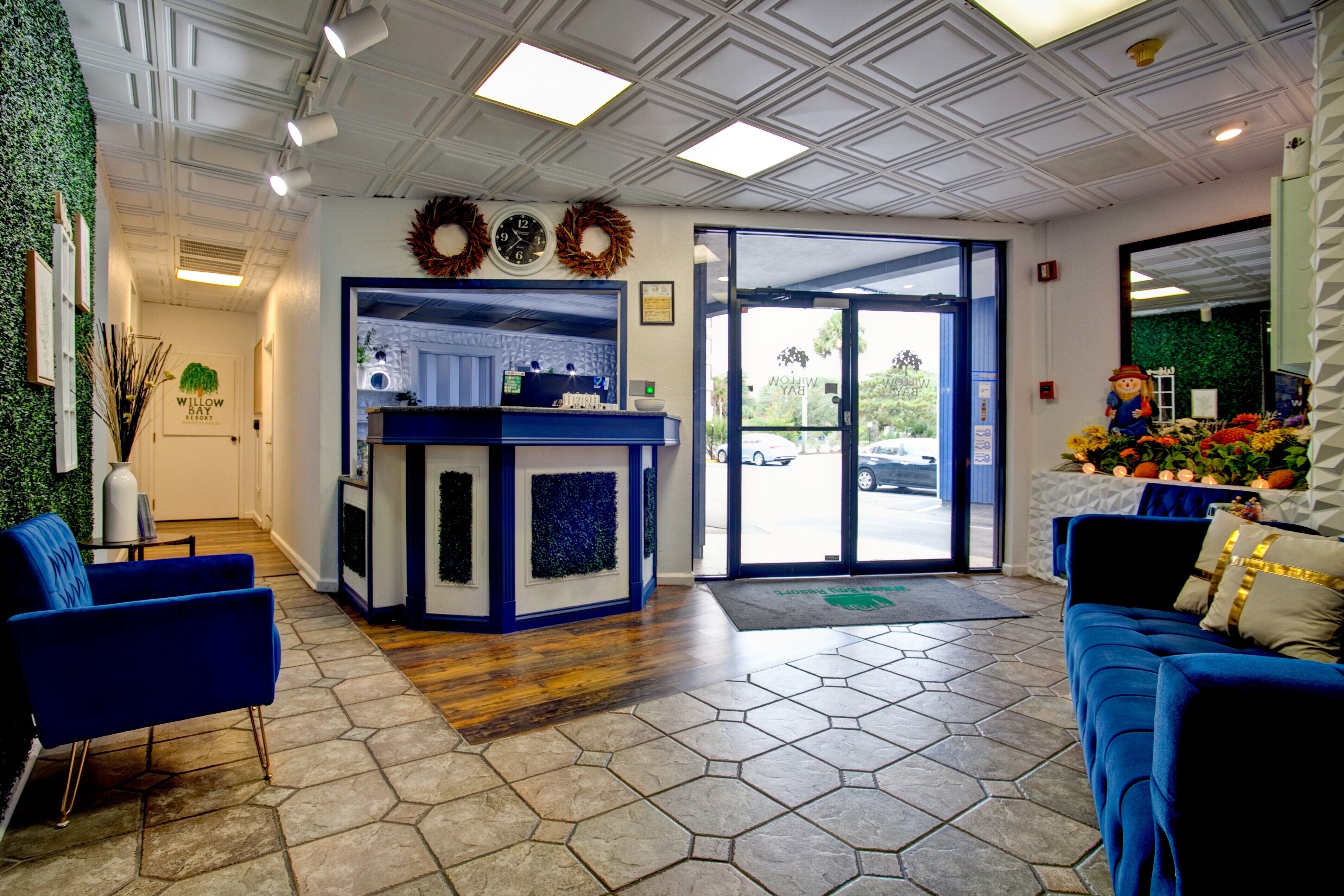 A reception area with a blue sofa, a reception desk, and a view of the outside.