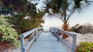 A wooden boardwalk leading to a beach with palm trees and dense foliage on either side. - Willow Bay Resort  (Myrtle Beach)