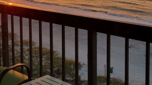 A sunset view from a balcony with a table and chairs. - Willow Bay Resort  (Myrtle Beach)