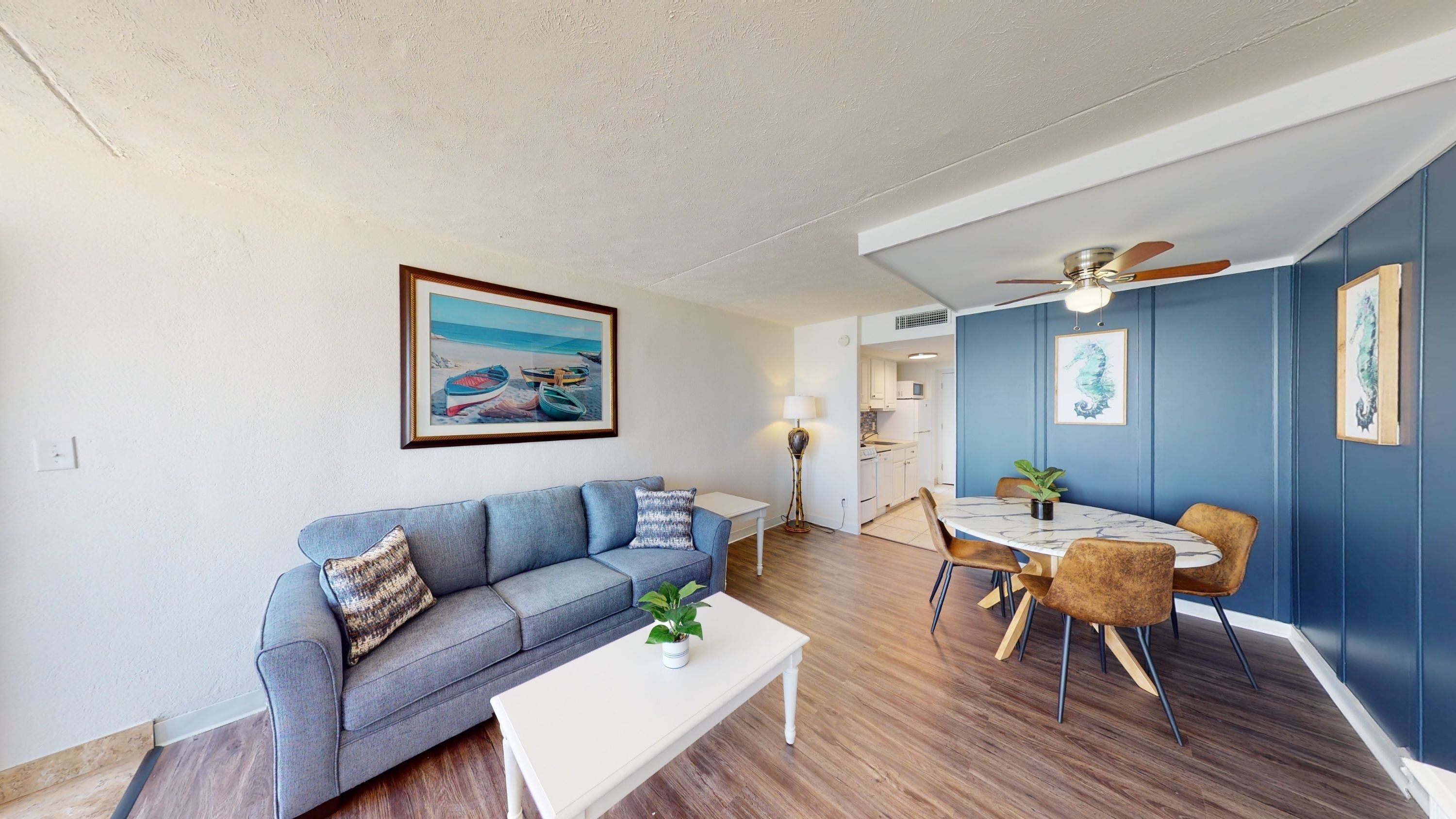 A living room with a sofa, coffee table, and a dining area with chairs and a table.