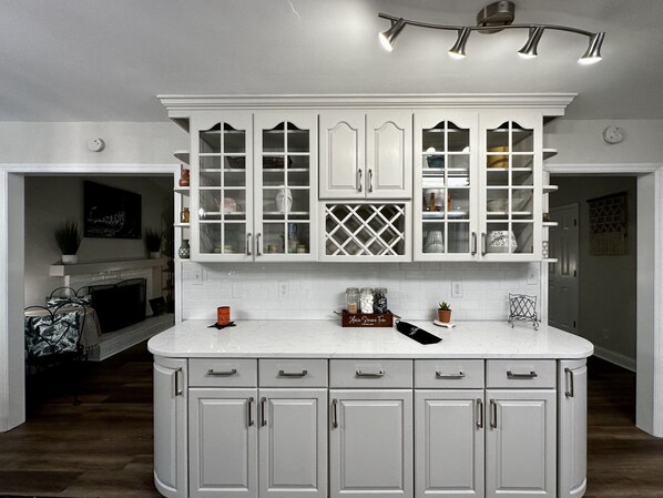 A kitchen with white cabinetry, a marble countertop, and a built-in wine rack.
