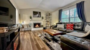 Una sala de estar con chimenea, sofá de cuero y ventilador de techo.
