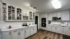Una cocina moderna con armarios blancos, suelo de madera y un microondas integrado.