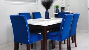 Un comedor moderno con una mesa blanca, sillas tapizadas en azul e iluminación colgante.