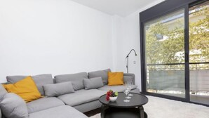Ein modernes Wohnzimmer mit einem grauen Ecksofa, einem runden Couchtisch und einer großen Schiebetür aus Glas.