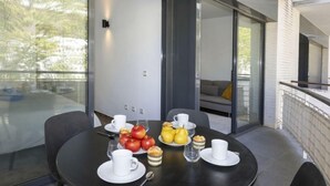 Ein zeitgemäßer Essbereich mit einem runden Tisch, gedeckt für ein Frühstück, mit Früchten, Gebäck und weißen Tassen.