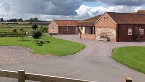 A farmstead with a stone barn, a gravel driveway, and a fenced pasture. - The Shamba, Bainvalley Cottages (Hemingby)