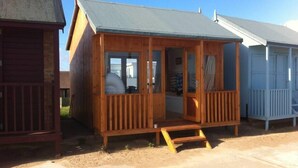 Une cabane en bois avec un porche, un petit hall d’entrée et une fenêtre.